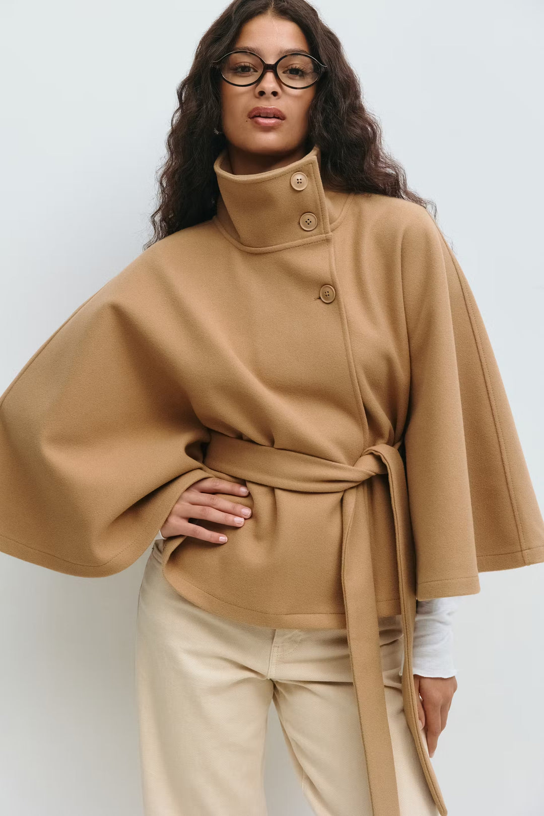 Beige cape jas met hoge kraag en knoopsluiting – close-up voorkant