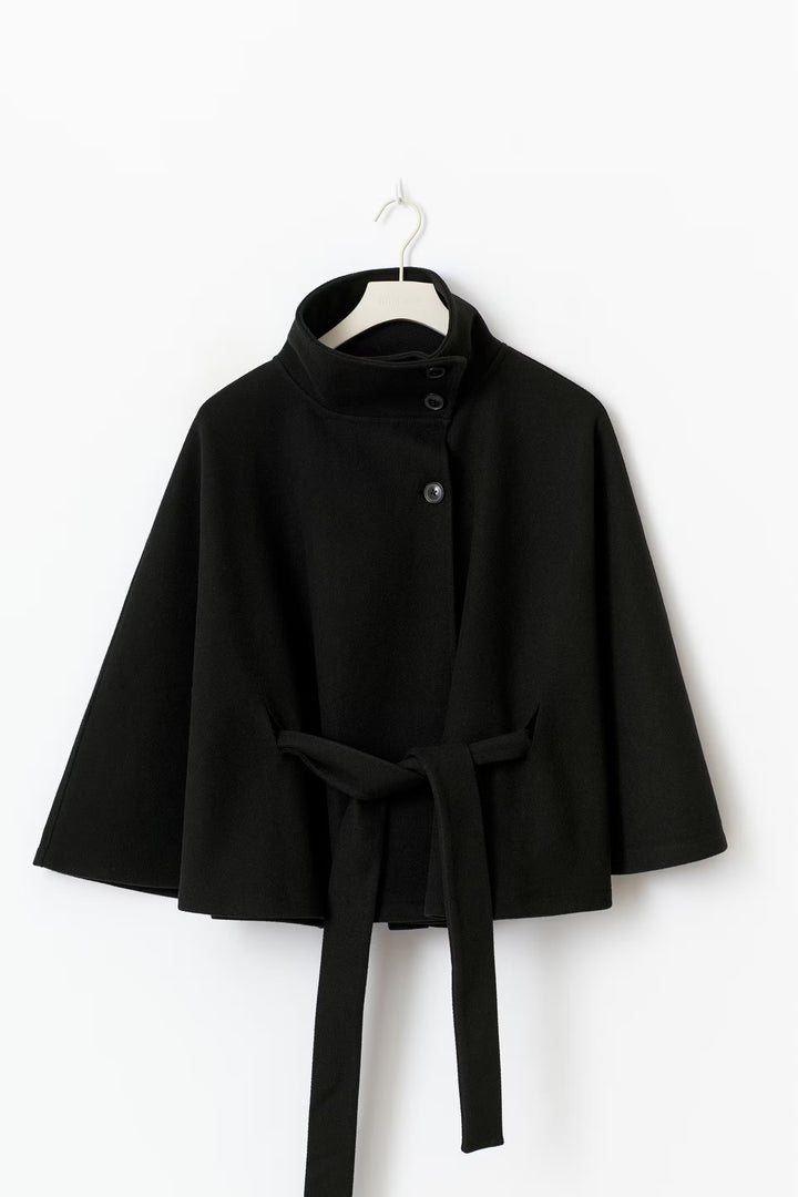 Zwarte cape jas met ceintuur en wijde pasvorm – volledige look